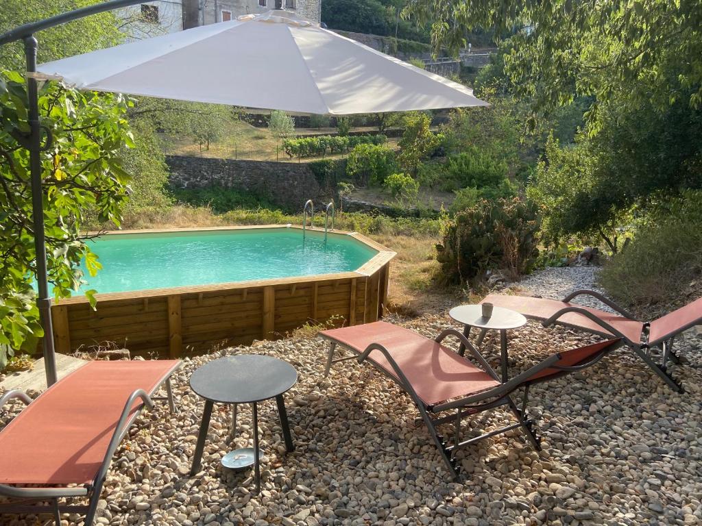 a pool with two chairs and a table and an umbrella at Magnifique gîte 75M2 avec terrasse 30m2, piscine, terrain de pétanque, et jardin en Cévennes in Meyrannes