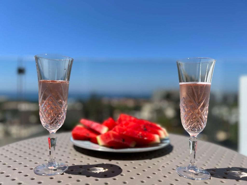 two champagne glasses sitting on a table with a plate of watermelon at Green Door Getaway in Limassol