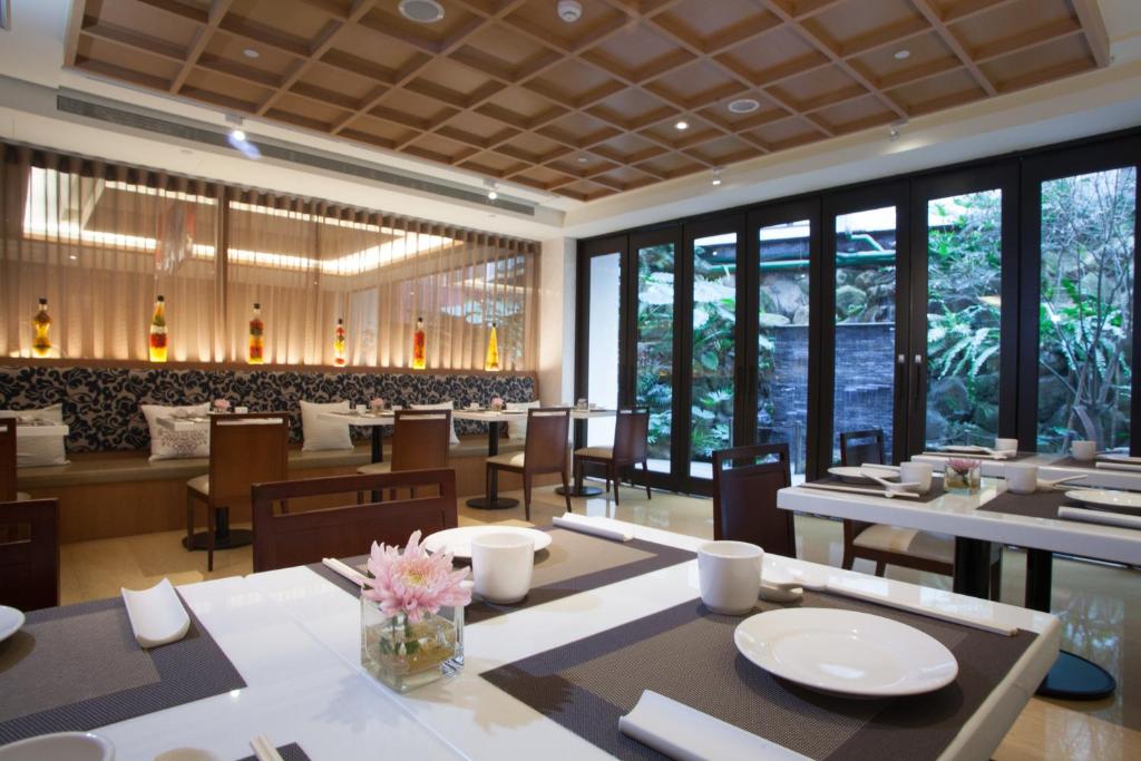 a dining room with tables and chairs and windows at Beitou Sweet Me Hot Spring Resort in Taipei