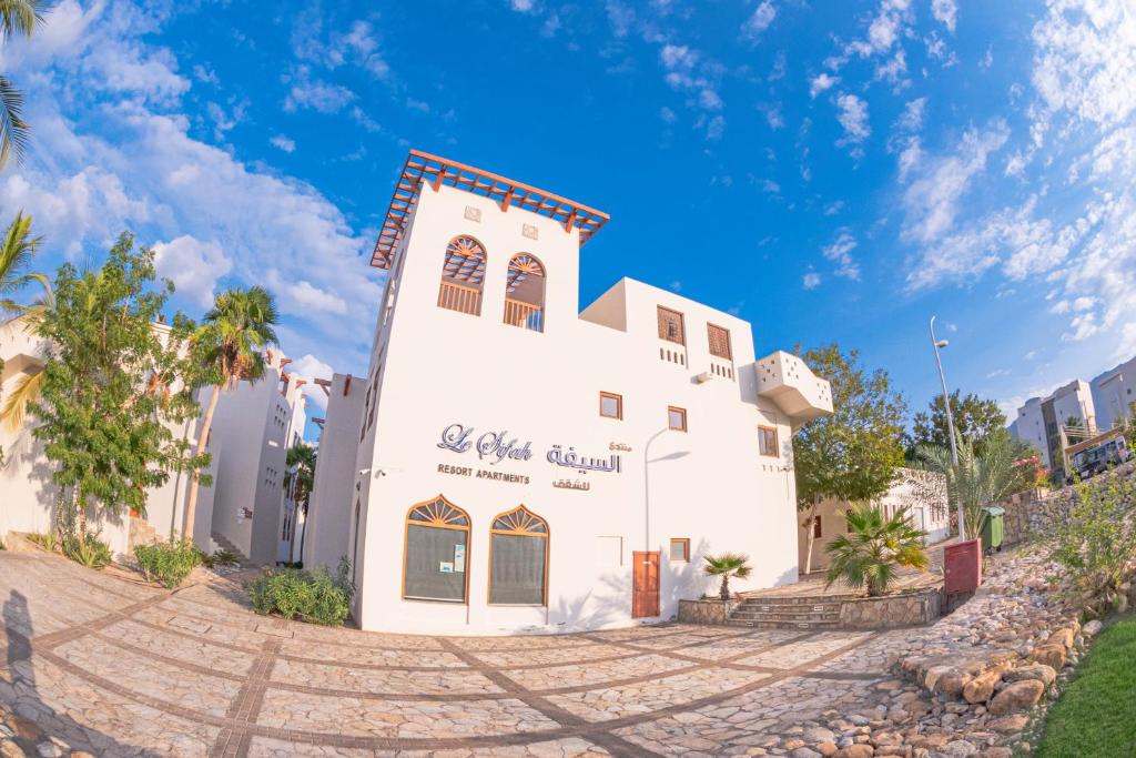 un edificio blanco al lado de una calle en Le Sifah - Marina View Apartments & Villa, en As Sīfah
