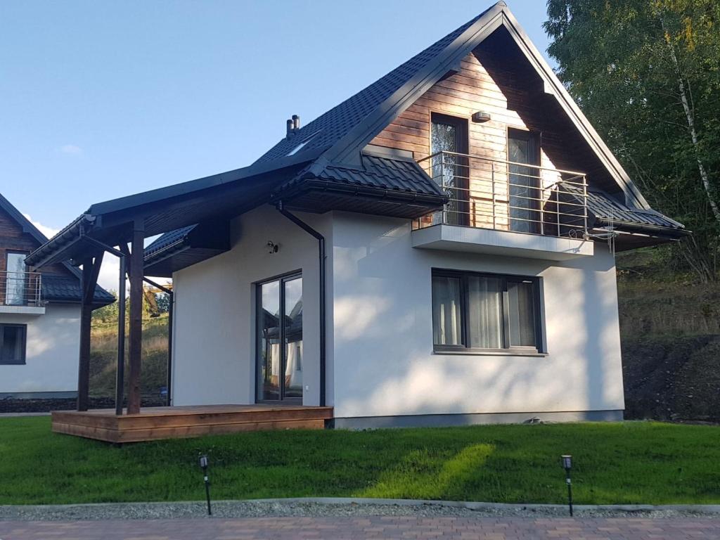 ein weißes Haus mit einem Gameradach in der Unterkunft Panskiemisie Domki Całoroczne sauna jacuzzi in Wetlina