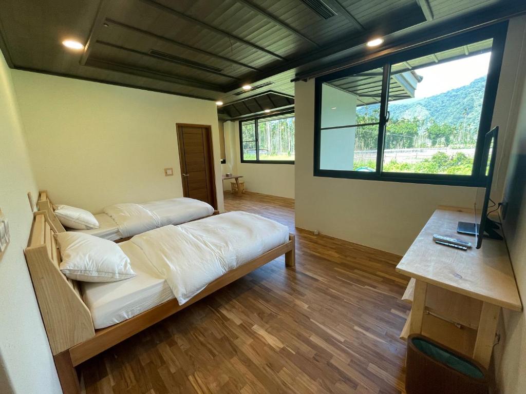 two beds in a room with a large window at 奕青民宿-梅酒 梅精 法國麵包plum winery guesthouse in Shuili
