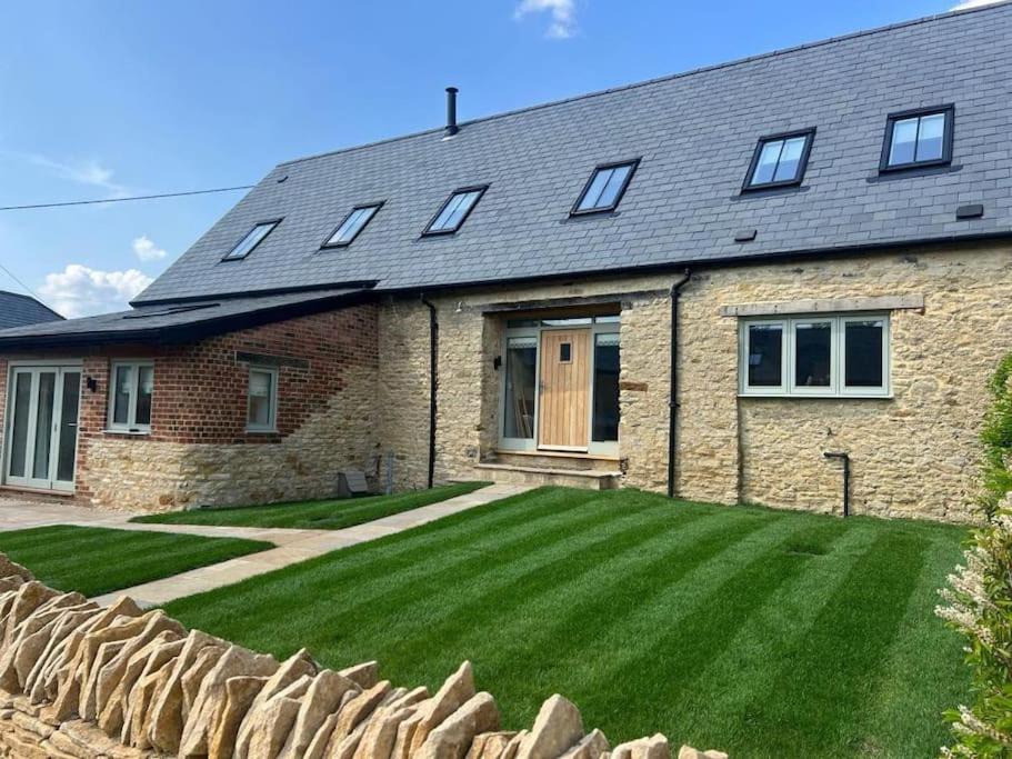 a brick house with a large lawn in front of it at Luxury Barn near Soho Farmhouse in Middle Barton