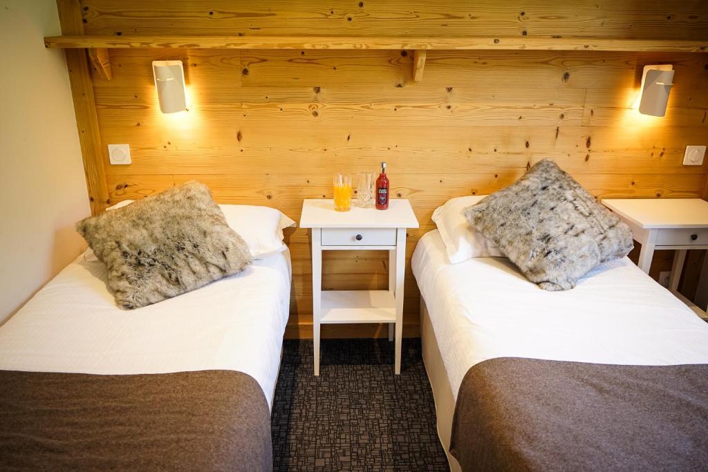 a room with two beds and a table with a night stand at Hotel Le Faranchin in Villar-dʼArène