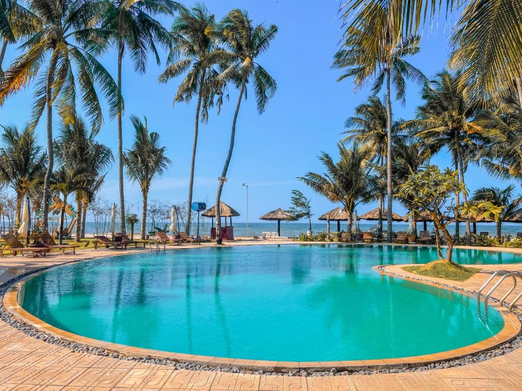 una piscina con palmeras y el océano en MUINE SUN AND SEA RESORT & GLAMPING, en Mui Ne