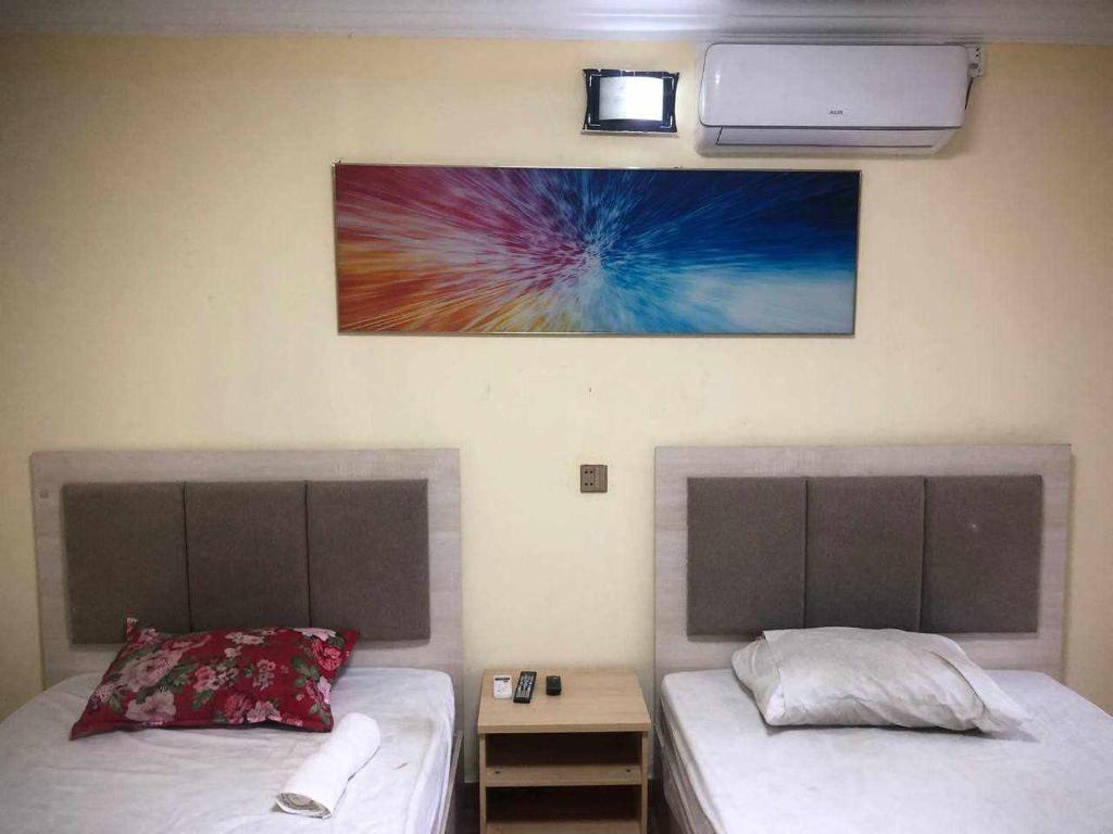 two beds in a room with a picture on the wall at Sea Inn Guesthouse Sihanoukville in Sihanoukville