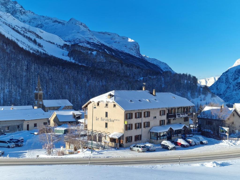 a town in the snow with mountains in the background at Hotel Le Faranchin in Villar-dʼArène