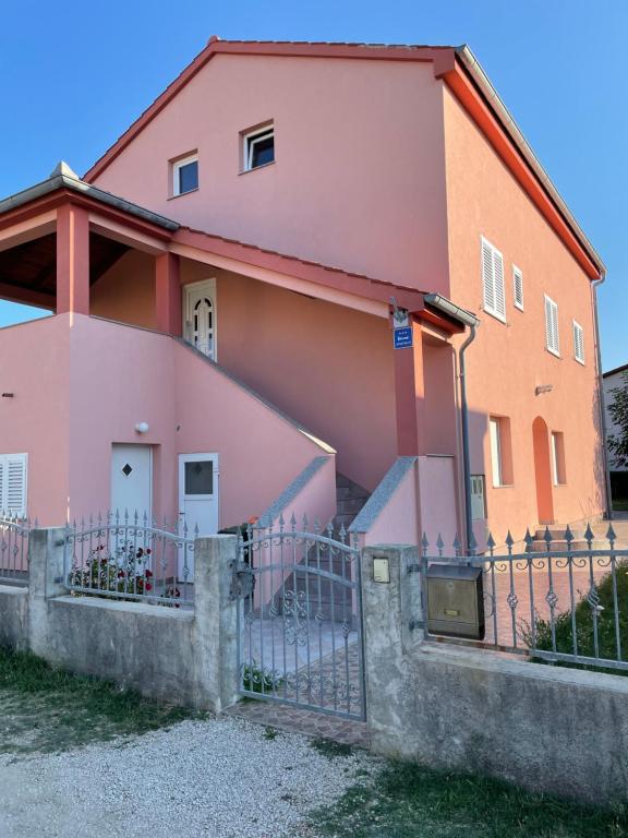 een roze huis met een hek ervoor bij Apartments Đurđa, Sabunike in Privlaka