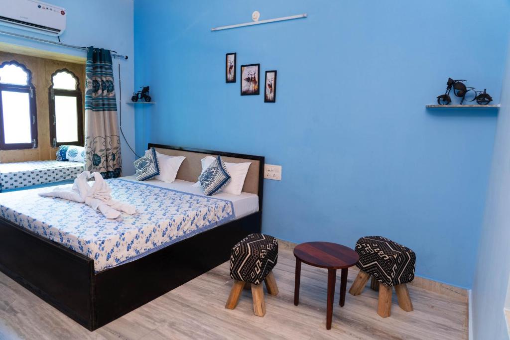 a bedroom with blue walls and a bed and two chairs at the new view in Jodhpur