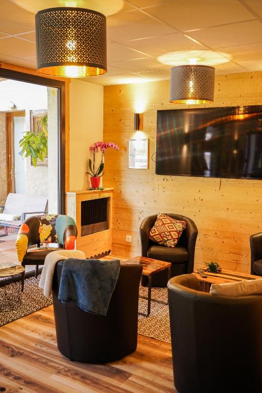 a living room with couches and chairs and a fireplace at Hotel Le Faranchin in Villar-dʼArène