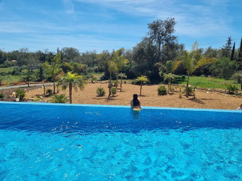 a woman sitting in the water in a swimming pool at Villa Das Alfarrobas Eco Design Cabin in Algoz