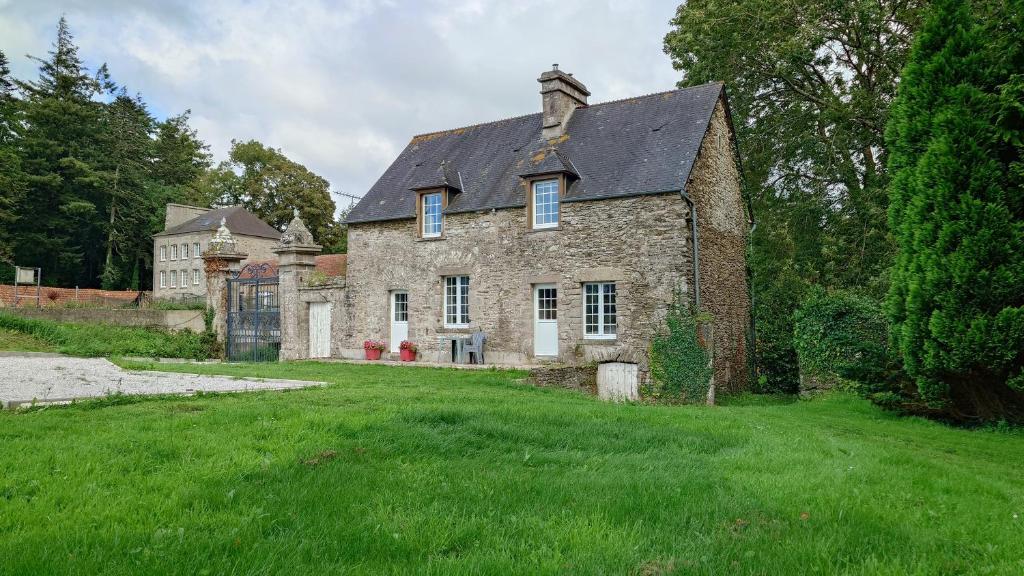 una vecchia casa in pietra in un campo di erba verde di Loge de la Saire a Gonneville