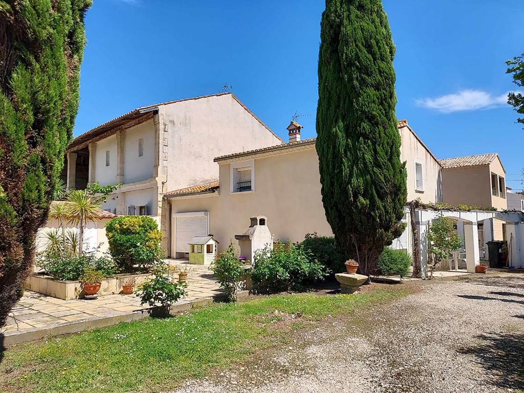 uma casa com uma grande árvore em frente em Villa Mariella em Arles