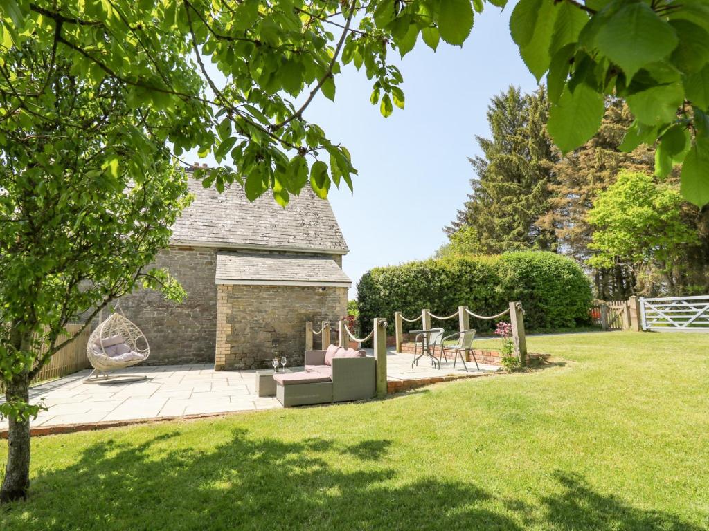 a garden with a patio in front of a building at St Marks School House in Llanwrthwl