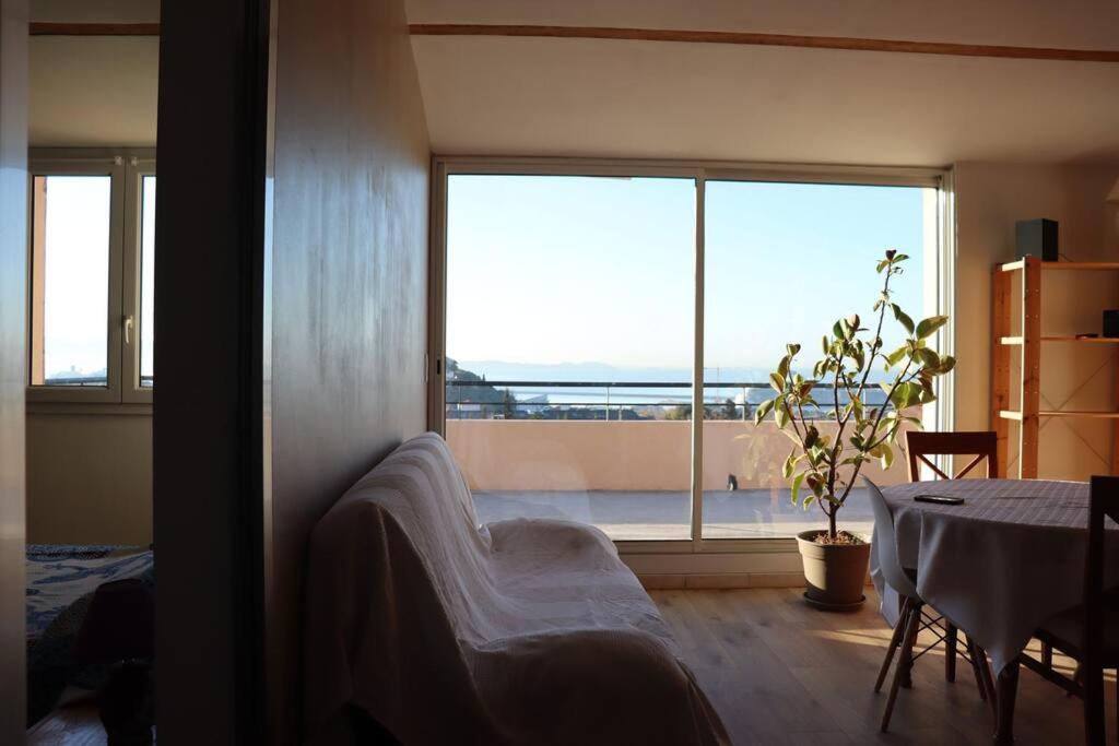 a living room with a table and a large window at Estaque Cozy nest with a magical view of the sea in Marseille