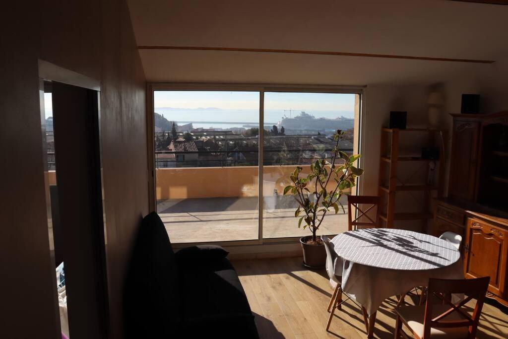 a living room with a table and a large window at Estaque Cozy nest with a magical view of the sea in Marseille