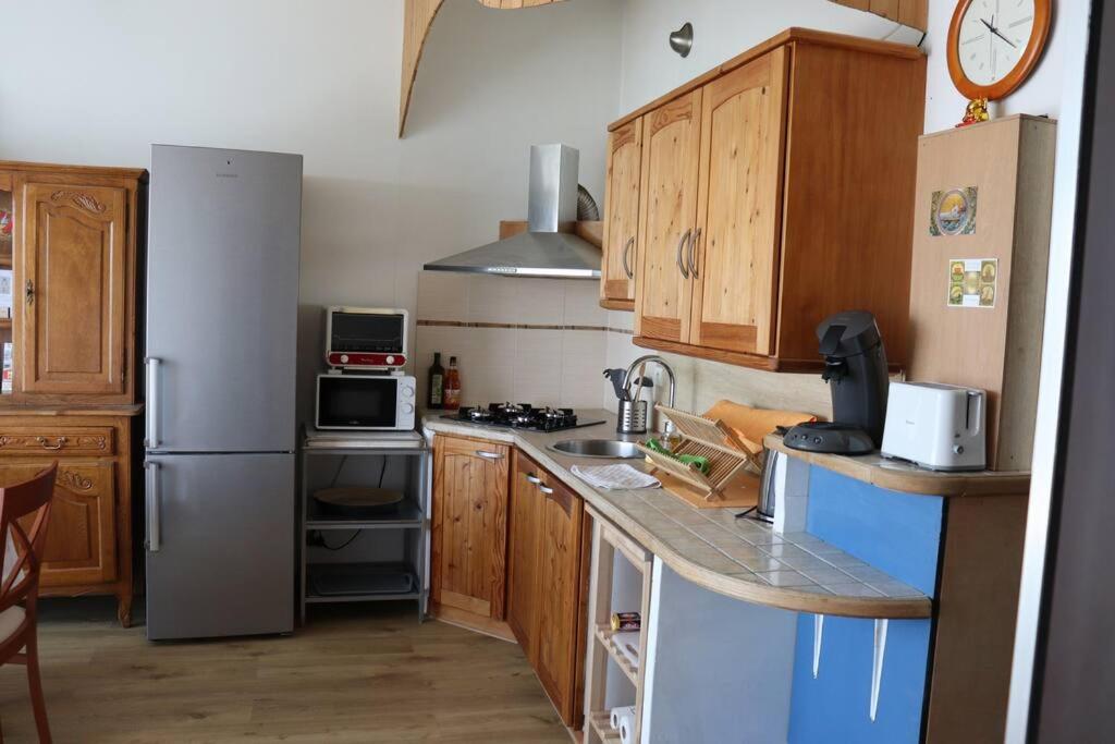 a kitchen with wooden cabinets and a stainless steel refrigerator at Estaque Cozy nest with a magical view of the sea in Marseille