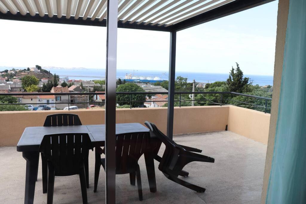 a table and chairs on a balcony with a view at Estaque Cozy nest with a magical view of the sea in Marseille