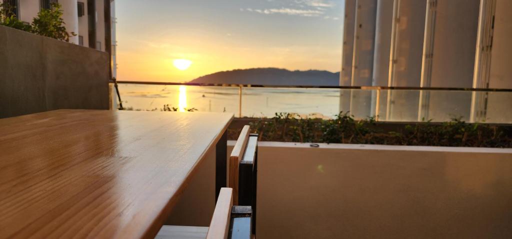 コタキナバルにあるThe Shore Ns Studio Suites Sea Viewの夕日を望むバルコニー(テーブル、椅子付)