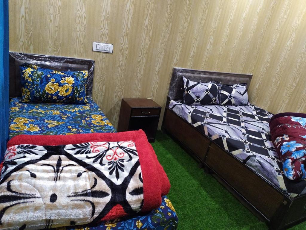 2 camas en una habitación con alfombra verde en P.k. Resort Kedar Valley Triyuginarayan road, Sonprayag, en Trijugi Nārāyan