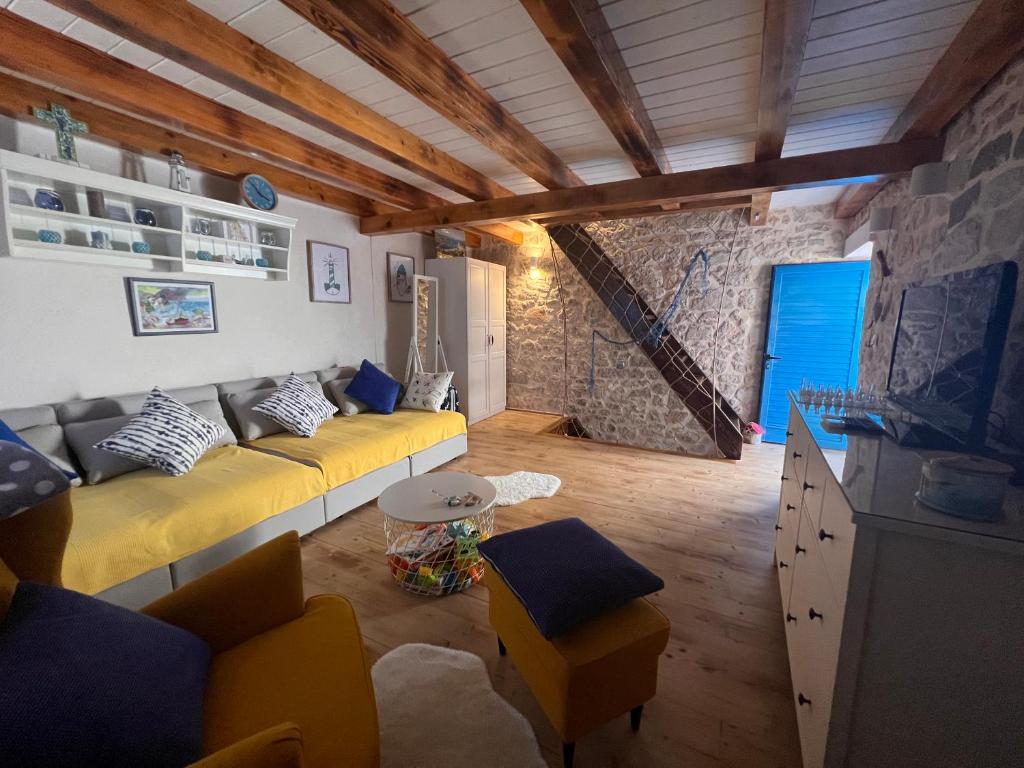 a living room with a yellow couch and a stone wall at Villa Tomitorija in Kaprije