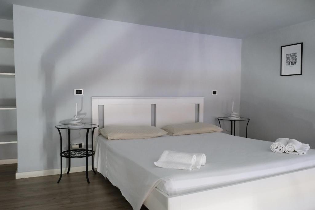 ein weißes Schlafzimmer mit einem weißen Bett und 2 Tischen in der Unterkunft Carega City Center Apartment in Verona