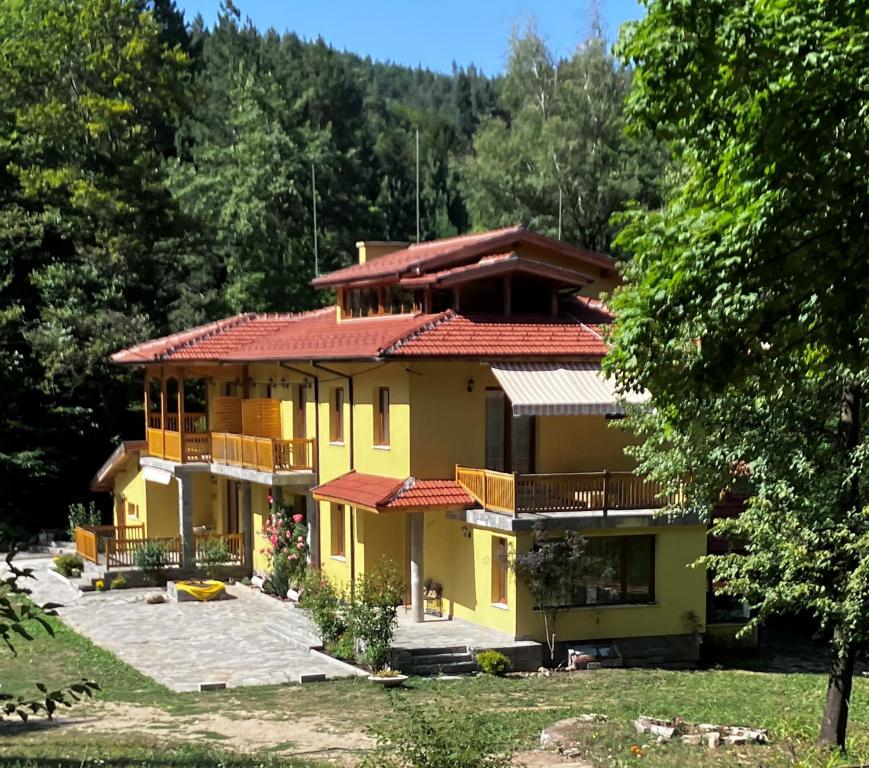 una gran casa amarilla con techo rojo en Вила Ренесанс Костенец, en Kostenets