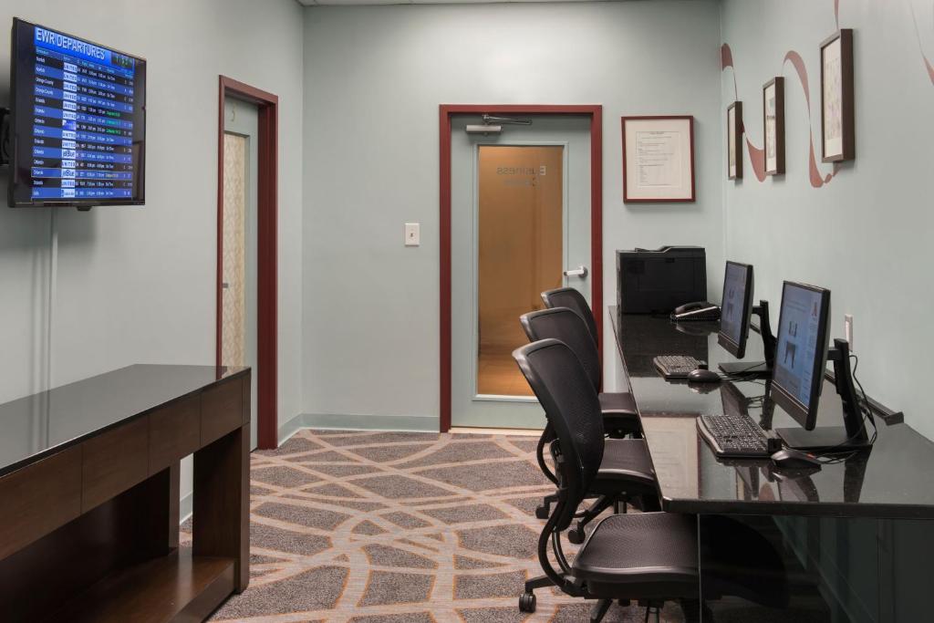 an office with a desk with chairs and a monitor at Newark Liberty International Airport Marriott in Newark