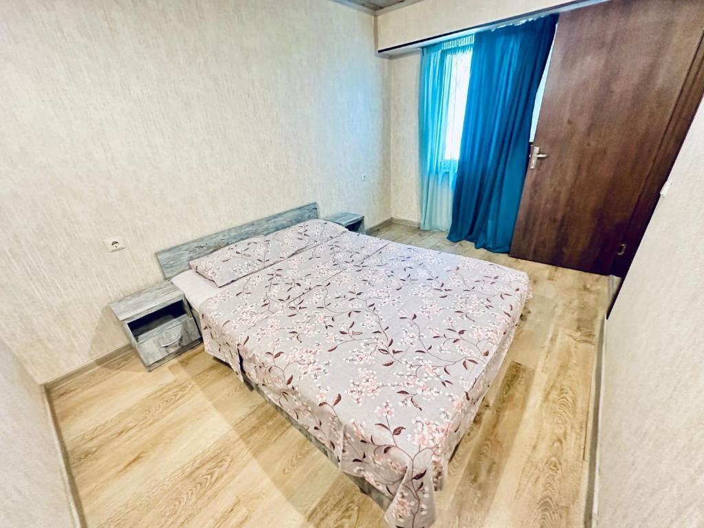 a small bedroom with a bed and blue curtains at Vato Home in Tbilisi City