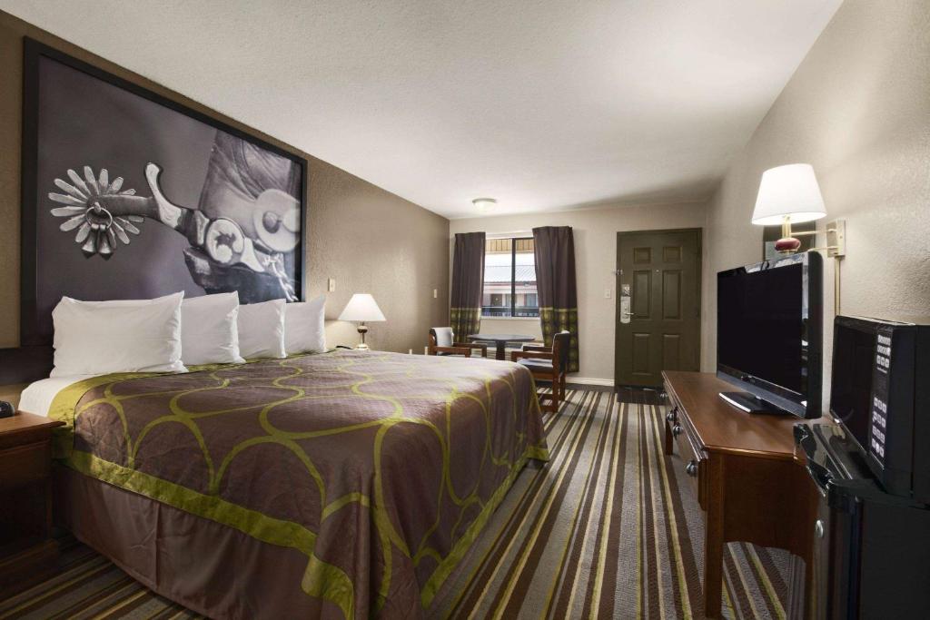 a hotel room with a bed and a flat screen tv at Super 8 by Wyndham Childress in Childress