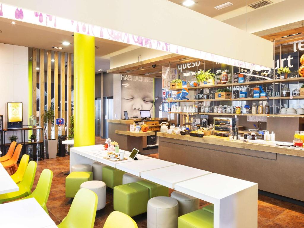 un restaurant avec une table blanche et des chaises jaunes dans l'établissement Ibis Budget Sevilla Aeropuerto, à Séville