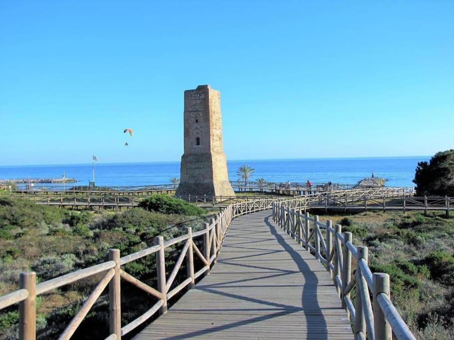 a boardwalk leading to a lighthouse on the beach at OleHolidays 624 Duplex Carib Playa 200 mts. playa in Marbella