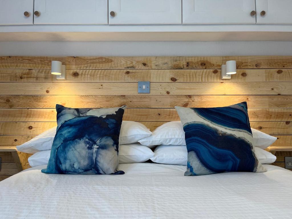 łóżko z dwoma niebieskimi poduszkami na górze w obiekcie Cornish Beach Lodge w mieście Torpoint