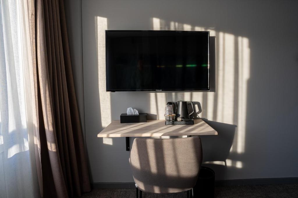 a room with a table with a television on a wall at Hotel Hvide Falk in Ilulissat