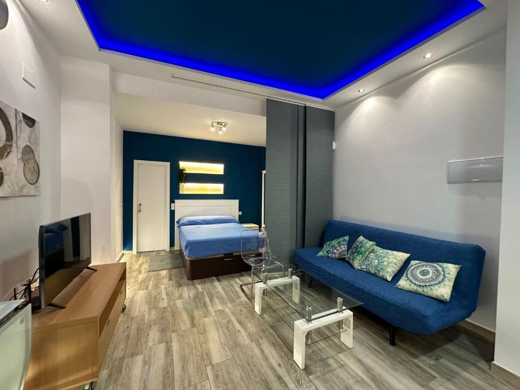 een woonkamer met een blauwe bank en een bed bij Loft Vialia Centro in Málaga