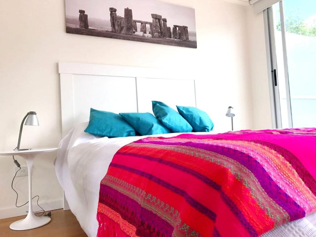 um quarto com uma cama com almofadas azuis e cor-de-rosa em Moderno departamento en Palermo em Buenos Aires