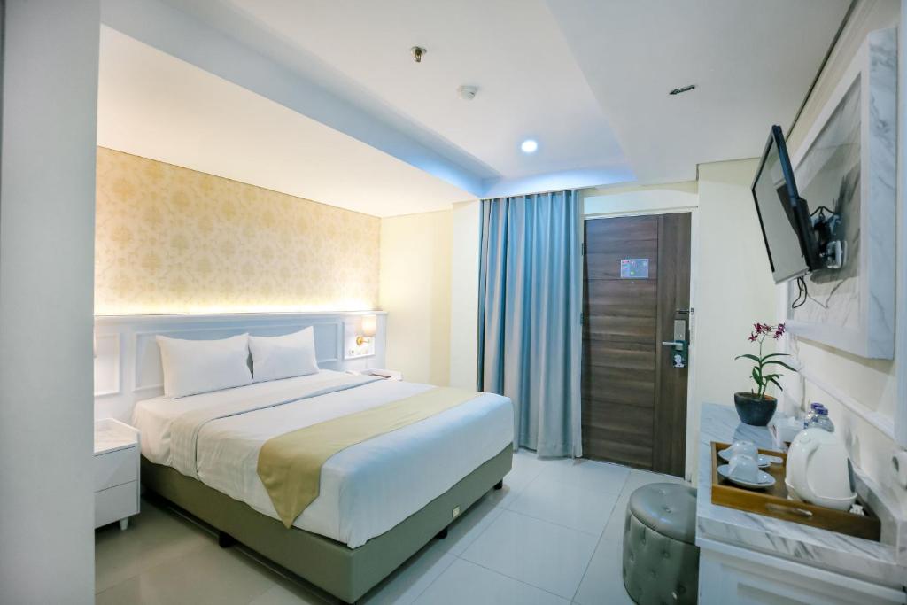 a hotel room with a bed and a television at The Cube Malioboro Hotel in Yogyakarta