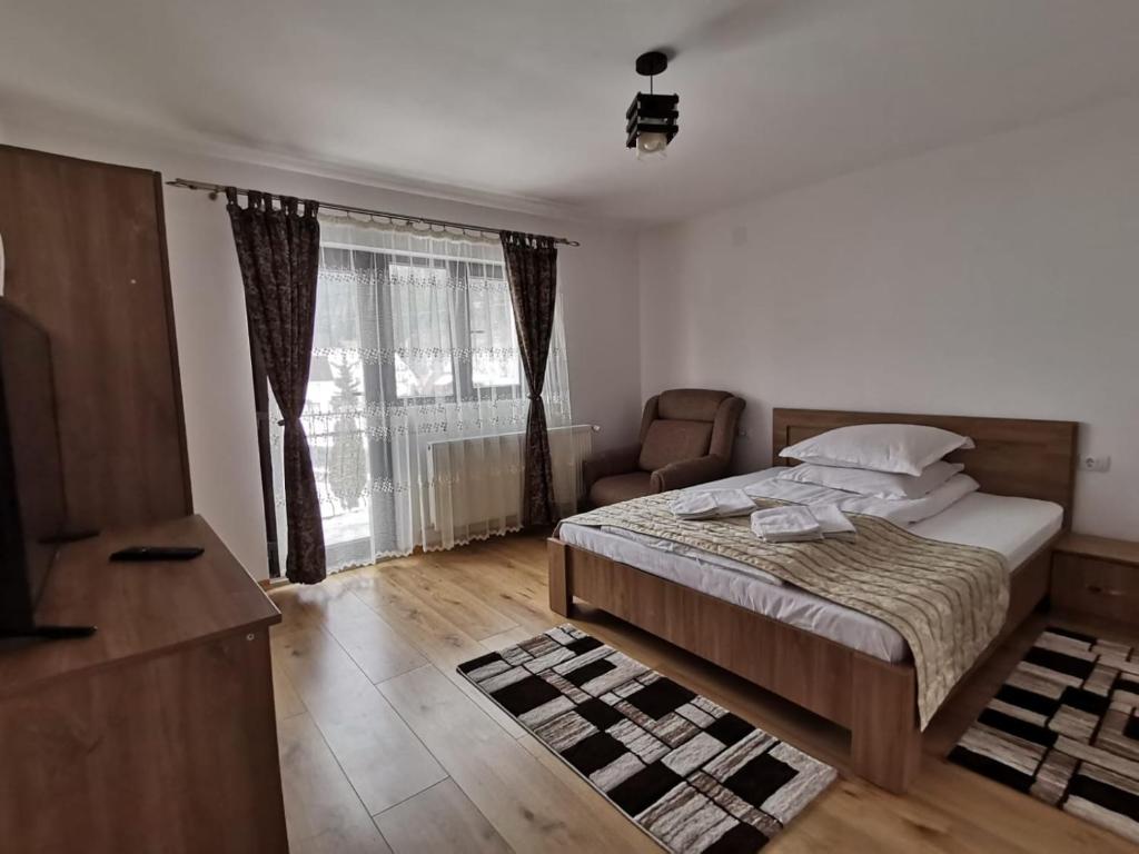 a bedroom with a bed and a chair and a window at Casa Dana Olteanu in Moieciu de Sus