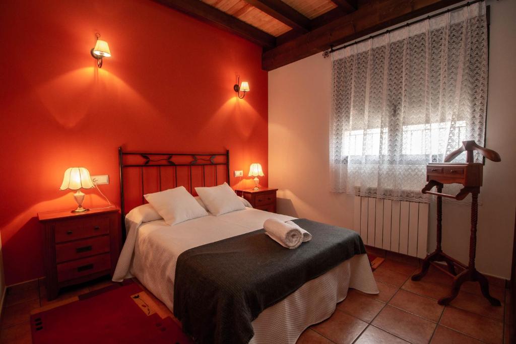 a bedroom with a bed with red walls and a window at El Rincón de Antonio in Monfarracinos