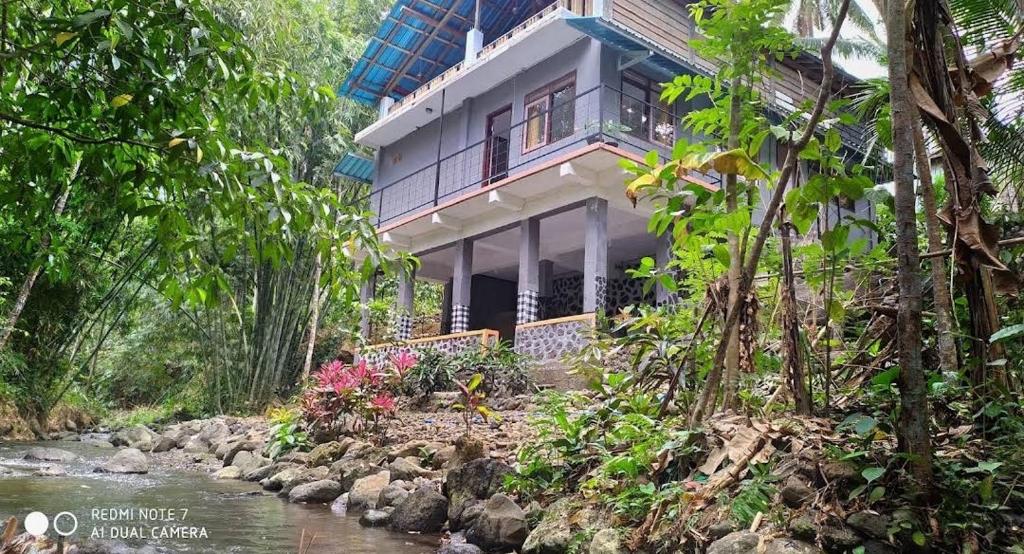 a house with a river in front of it at Peno Homestay in Sumberbuluh