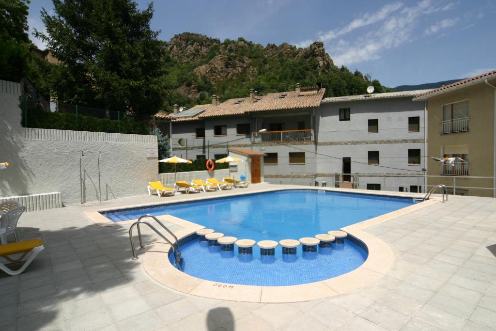 a large swimming pool with chairs and a building at Apartaments Sant Antoni in Ribes de Freser