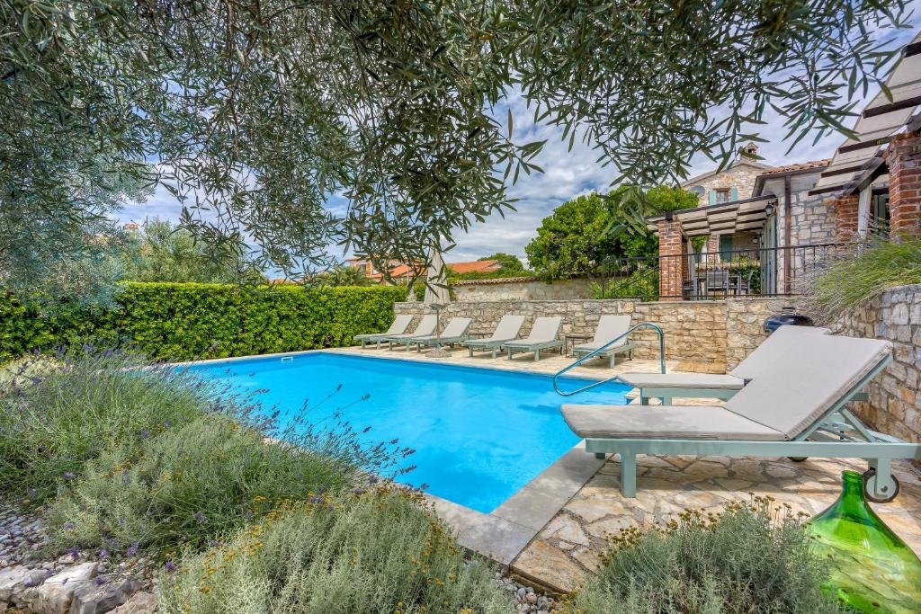 a pool with lounge chairs next to a house at Vila Aryana With Pool - Happy Rentals in Sveti Lovreč Pazenatički