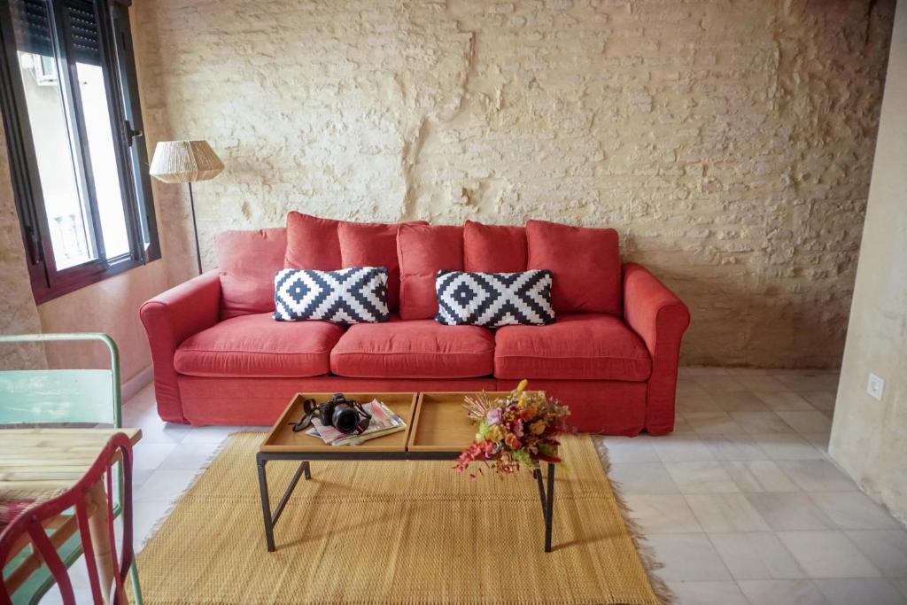 ein rotes Sofa im Wohnzimmer mit Couchtisch in der Unterkunft San Diego Cathedral Sevilla in Sevilla