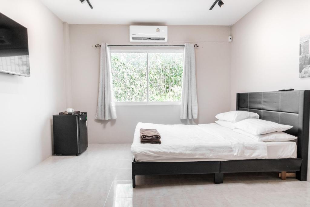 a white bedroom with a bed and a window at Breakers Hotel Rawai in Phuket