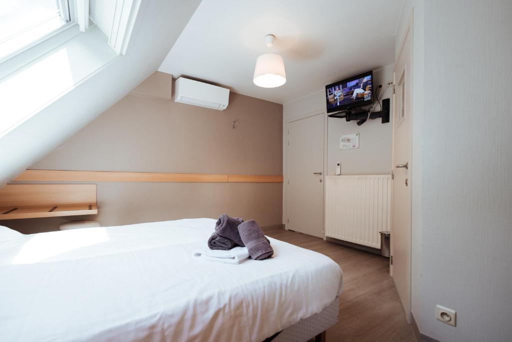 a bedroom with two beds and a tv on the wall at Hotel Brasserie De Beiaard in Torhout