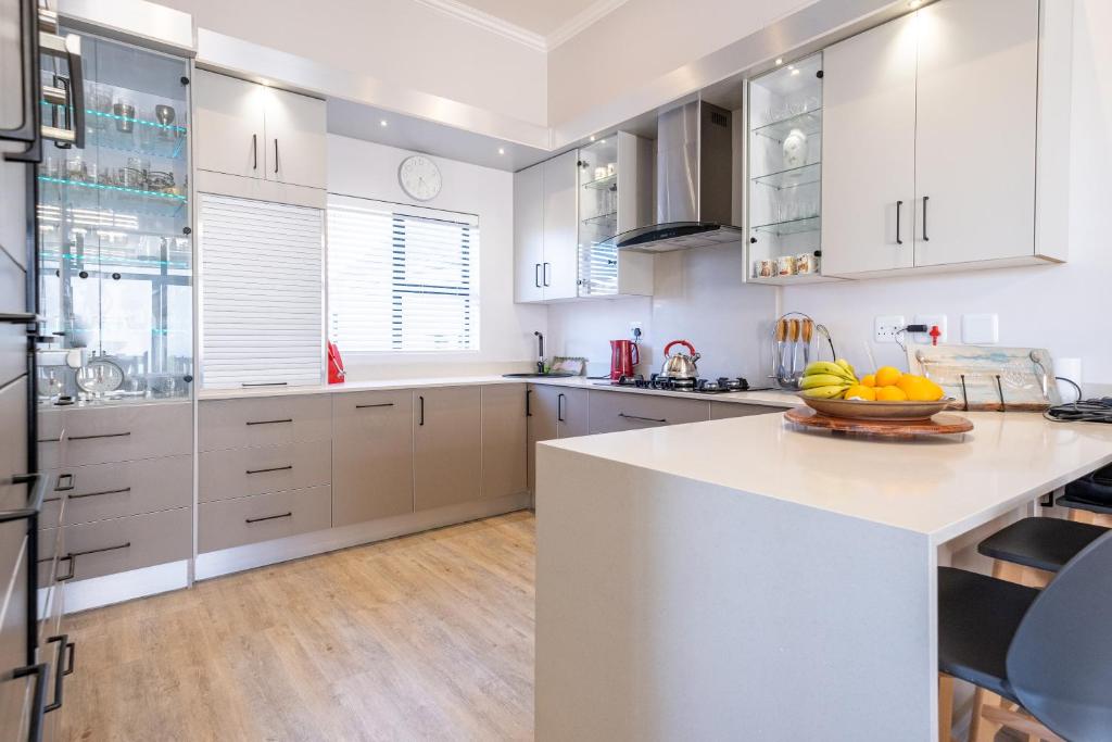 a kitchen with white cabinets and a bowl of fruit on a counter at The Halfway House @ Kingswood Golf Estate in George