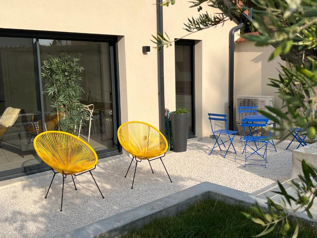 3 sillas y sillas amarillas frente a un edificio en Villa Gaïa - logement entier - 2 suites parentales avec salles de bain privatives - parking privé - 10 minutes Eurexpo - Aéroport - Groupama Stadium, en Genas