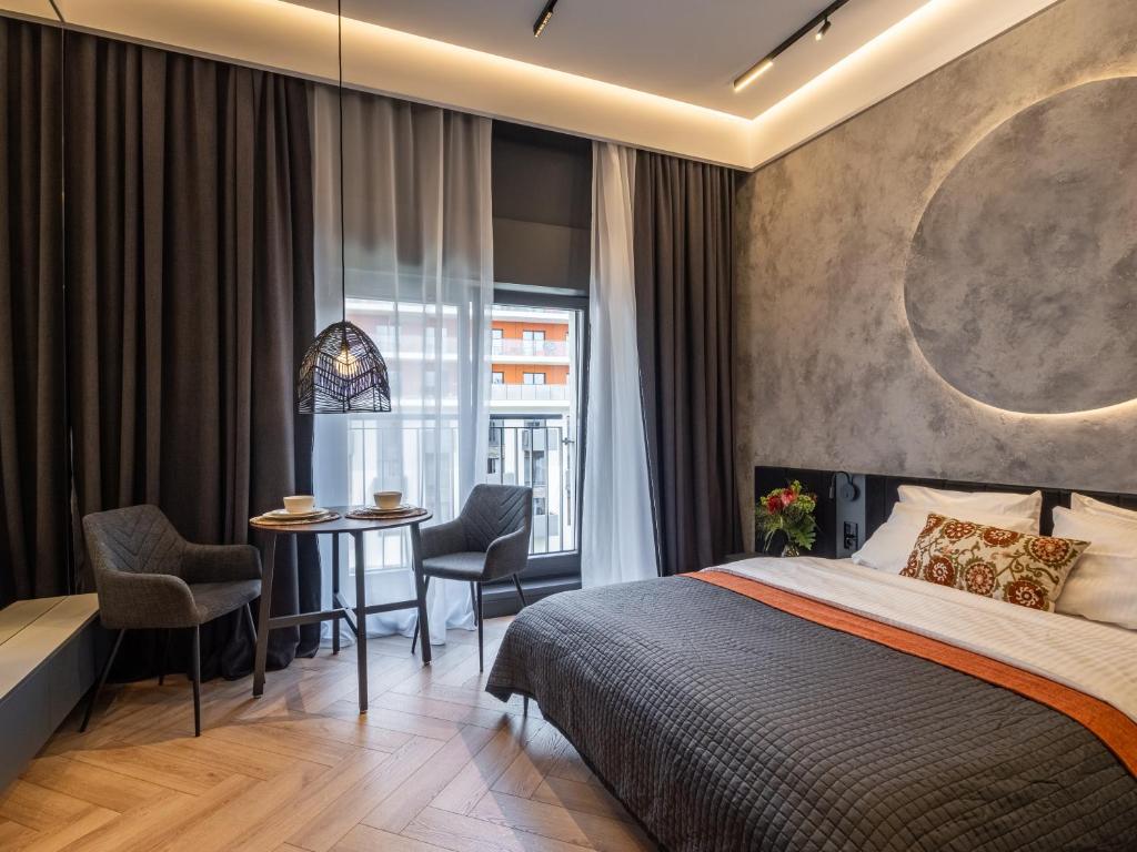 1 dormitorio con 1 cama, mesa y sillas en Loft House Apartments, en Wroclaw