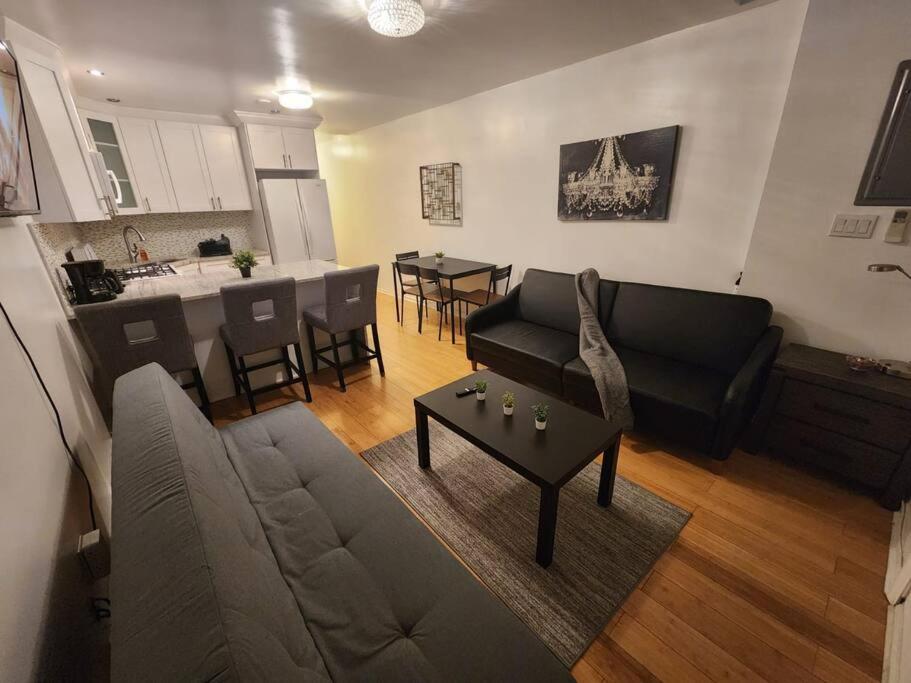 a living room with a couch and a table and a kitchen at Cosy Modern Home Mins to NYC! in Union City