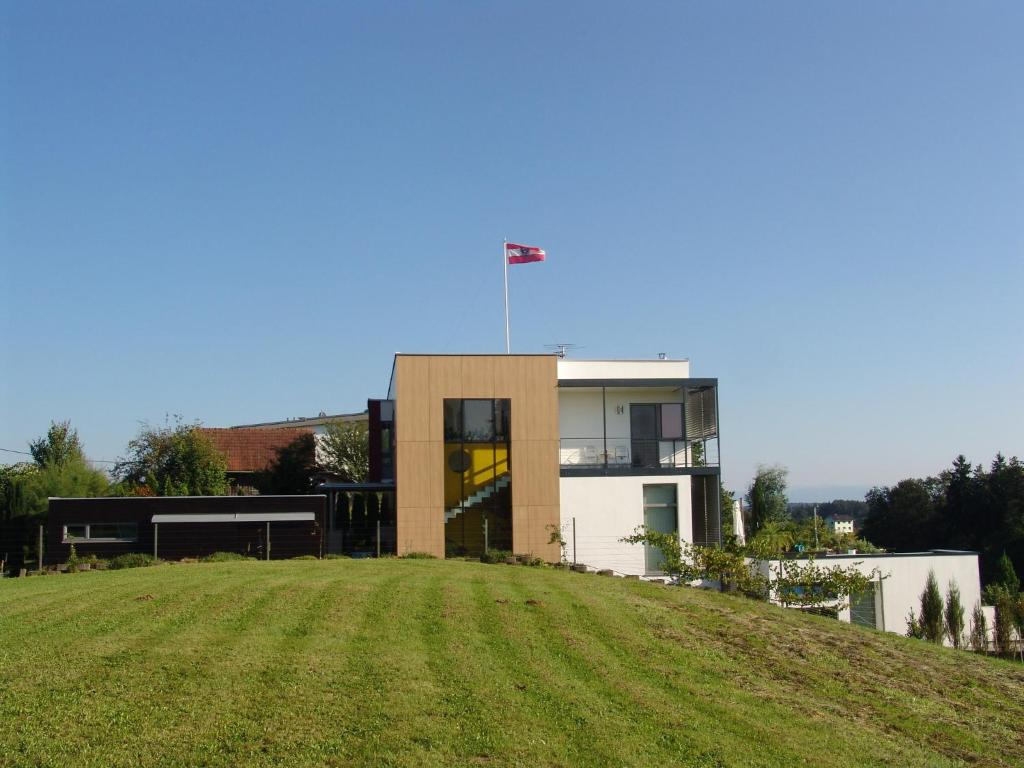 una casa en la cima de una colina con un campo de hierba en Appartement Architektenhaus - Pool - Fernsicht, en Lannach